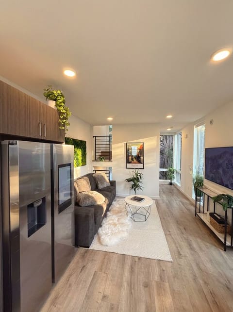 Bright modern living area with sleek kitchen, big TV, and cozy sofa lounge.