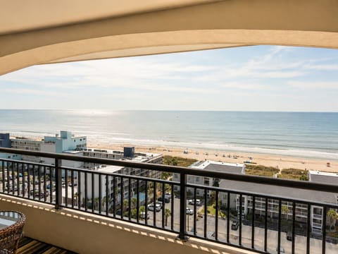 The property offers sweeping ocean views overlooking a sandy beach and coastal buildings, providing a scenic coastal setting for guests.