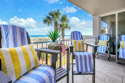 Settle into your private balcony with ocean breezes and cheerful striped cushions—your perfect spot to sip morning coffee or watch the waves roll in beyond the palms.