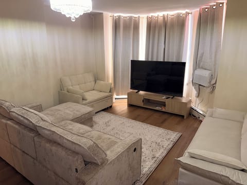 Cozy living room with plush seating, large TV, and elegant chandelier