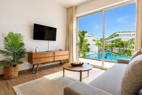 Bright living room with smart TV and large windows opening to the pool view