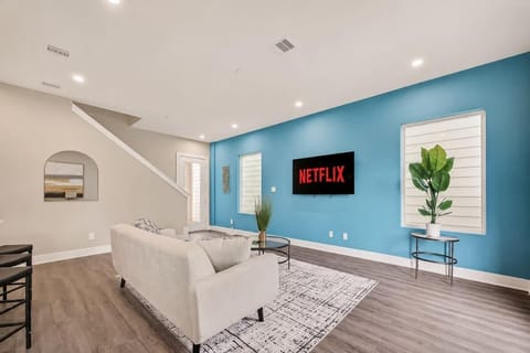 Stylish living space with a wall-mounted Smart TV, sleek hardwood-style flooring, and contemporary pendant lighting.