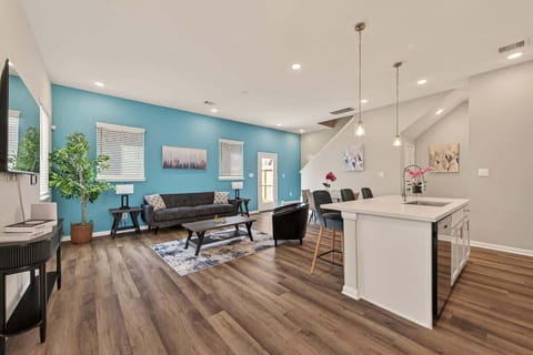 Relax in this bright, open-concept living room featuring a plush sofa, wall-mounted Smart TV, and a vibrant teal accent wall.