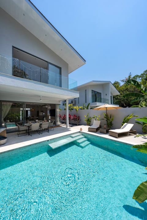 Sparkling private pool with comfortable sun loungers surrounded by modern tropical architecture