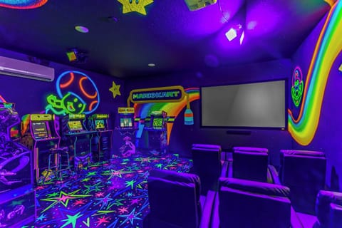 Enjoy a vibrant arcade and home theater room with neon lighting and classic game machines.