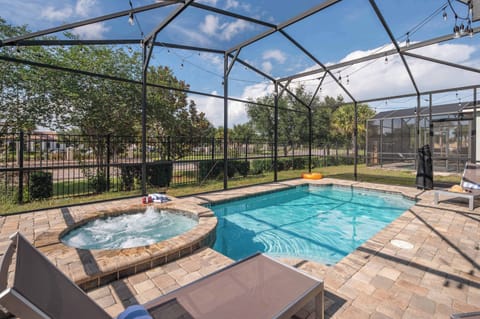 Relax by the screened pool and hot tub area with lounge chairs and string lights.