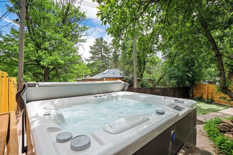The 3-person saltwater hot tub sits tucked into the corner of the fenced backyard with open sky above and tree cover on all sides. 
