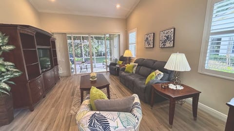 Welcome home! This spacious, inviting living room features warm wood-look flooring, a large media console, and expansive sliding glass doors that open to a private outdoor view.