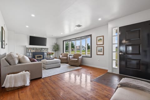 Bright living room with hardwood floors, big windows, and cozy fireplace