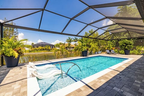 Sparkling screened-in pool with lounge chairs overlooking the water - the heart of this Cape Coral retreat.