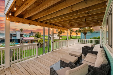 Spacious covered deck with comfortable outdoor seating, wood plank flooring, and open neighborhood views. Ideal for outdoor relaxation and enjoying the coastal breeze in Jamaica Beach.