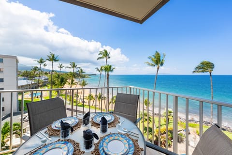 Oceanfront lanai with a four-seat dining set, perfect for enjoying meals or drinks while overlooking Kamaole Beach and the turquoise waters.