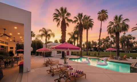 Luxurious pool area with lounge chairs pink umbrellas and park