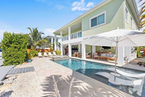 Waterfront Pool & Spa: Blue Keys skies, a glowing pool, and loungers steps from the patio.