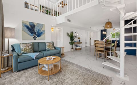 The open-concept living area features soaring ceilings and a charming spiral staircase leading to the loft.