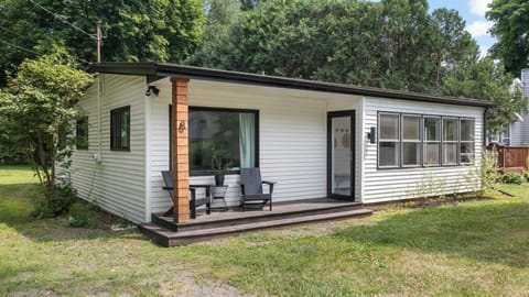 Charming cottage with covered porch, outdoor seating, and wooded setting