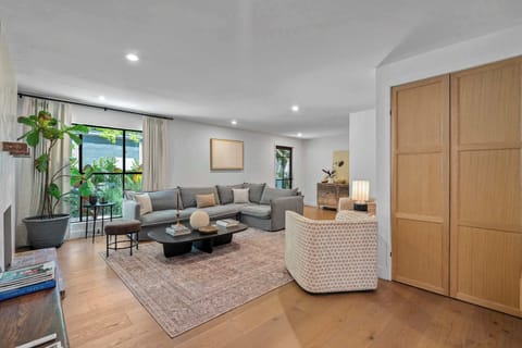 Main-floor great room with deep sectional sofa, hardwood floors, and floor-to-ceiling garden windows