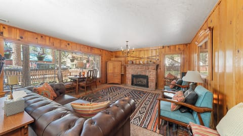 Living room includes large windows, sofa, armchairs, and dining table.