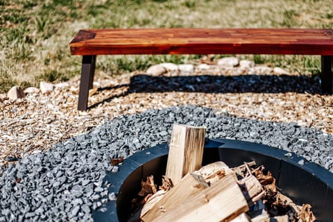 Enjoy warm evenings by the fire pit with rustic wooden seating, inviting relaxation and connection.