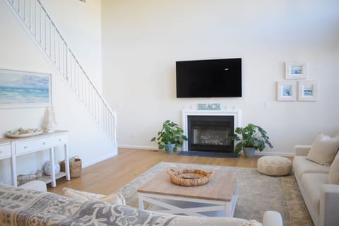 Bright coastal living room with fireplace, TV, and airy open design