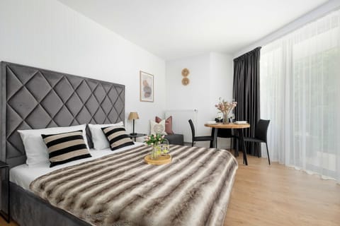 A wide shot of the bedroom emphasizes its spaciousness, connecting comfortable relaxation areas with a functional exit to the terrace. Warm lighting and textiles create a homely atmosphere.