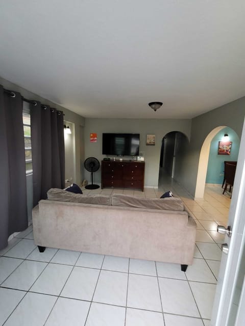 Bright, cozy living room with TV, tile floors, and charming archways