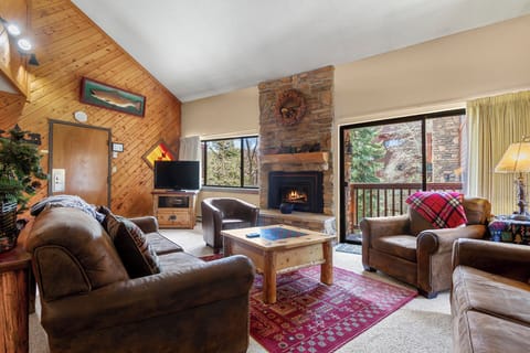 Curl up in this inviting living room where warm wood tones, plush leather seating, and a crackling stone fireplace create your perfect mountain retreat after a day of adventure.