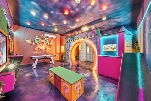 Step into a vibrant playroom filled with whimsical decor and colorful accents, featuring a playful slide and unique archway. The ceiling’s twinkling lights create a fun atmosphere, perfect for kids and adults to enjoy together.