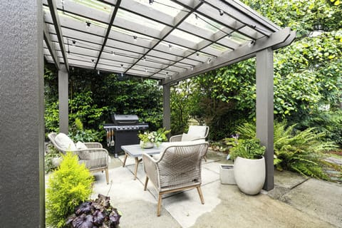 Covered garden patio with cozy seating, string lights, and private BBQ grill