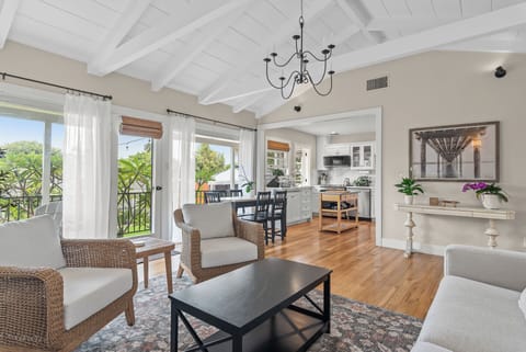 Gather and unwind in the open-concept living and dining area, featuring vaulted ceilings, abundant natural light, comfortable seating, a smart TV, and easy access to the outdoor patio.