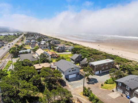 Aerial view of a coastal neighborhood nestled between ocean and hills, with beach access and scenic surroundings defining the area.
