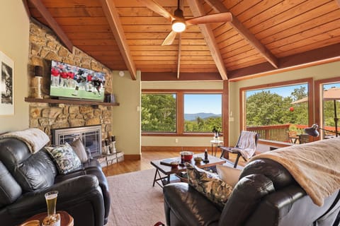 Soak in Breathtaking Mountain Views from This Stunning Living Room, Featuring a Striking Stone Fireplace for Chilly Evenings and Direct Access to a Sun-Drenched Deck — the Perfect Spot to Relax, Unwind, and Take in the Scenery Year-Round!
