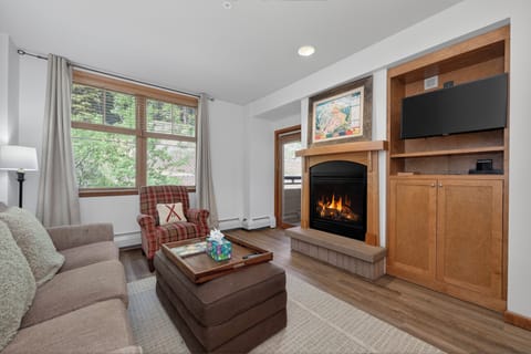 Curl up with a book by your crackling fireplace, enjoying views of the trees outside. The warm wood tones, flat-screen TV, and cozy seating create a peaceful retreat after your mountain adventures.
