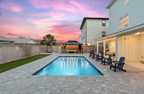 Private poolside retreat with lounge seating, string lights, and a beautiful sunset backdrop.