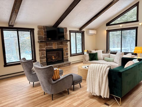 Vaulted, beamed family room with a stone gas fireplace—cozy in every season
