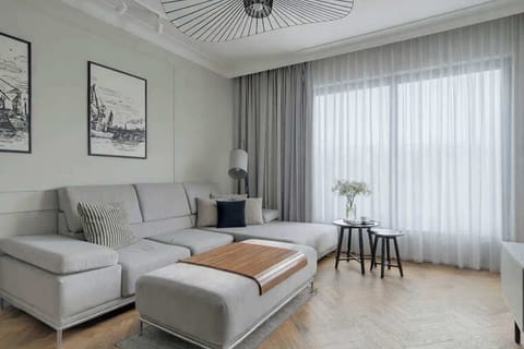 Sercem apartamentu jest jasny, słoneczny salon, w którym znajduje się wygodna, rozkładana sofa ustawiona naprzeciwko telewizora. To idealna przestrzeń do relaksu po intensywnym dniu, a jednocześnie dodatkowe miejsce do spania.
