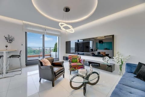 Jasny salon wyposażony jest w wygodną, rozkładaną sofę, designerskie fotele oraz telewizor z telewizją kablową i Smart TV, zapewniające idealną przestrzeń do relaksu po dniu pełnym wrażeń.