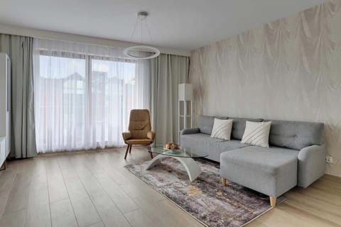 W salonie znajduje się rozkładana sofa zapewniająca dodatkowe spanie, a jasne wnętrze z designerskimi akcentami i dużymi oknami tworzy przytulny, nowoczesny klimat.