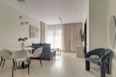 Przestronny salon został urządzony w nowoczesnym, stonowanym stylu. Centralnym elementem części wypoczynkowej jest duża, rozkładana sofa w odcieniu eleganckiej szarości, która zapewnia wygodne miejsce do relaksu.