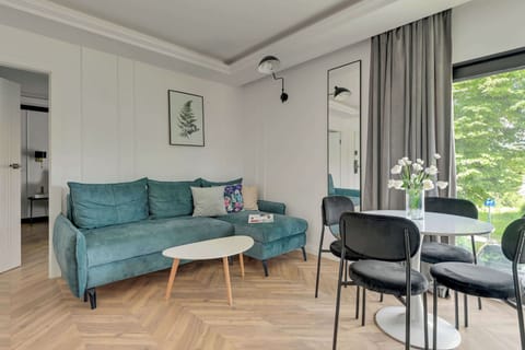 Głównym pomieszczeniem apartamentu jest przestronny salon, który pełni funkcję zarówno strefy wypoczynkowej, jak i jadalnianej. Znajduje się w nim wygodna rozkładana sofa, zapewniająca dodatkowe miejsce do spania. 