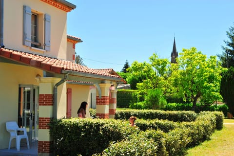 Ground-floor terrace with a private garden view — Nérac's church spire rises above the trees just beyond the hedge.