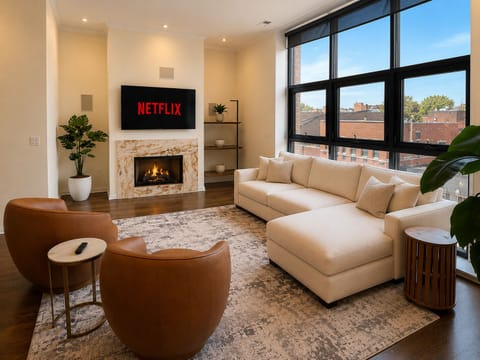 Bright modern lounge with fireplace, big windows, and cozy sectional