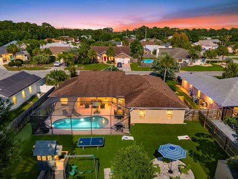 Welcome to your ultimate backyard oasis! This stunning aerial view shows off the fully screened pool, turf yard, putting green, playset, ping-pong table, cornhole, and patio seating. There is endless outdoor entertainment for everyone in your group!