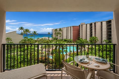 Ocean view lanai with a two-seat dining set overlooking tropical grounds.