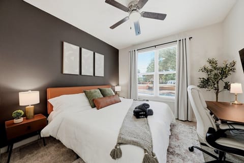 Moody bedroom w/ dark accent wall, patio access & neatly dressed bed.