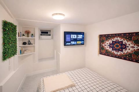 Separate bedroom with queen-size bed, smart TV, AC and built-in storage.