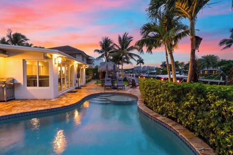 Waterfront poolside retreat with sunset skies, tropical palms, and canal views.