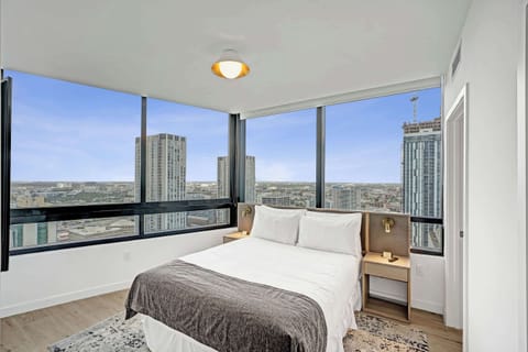 Wake up to breathtaking skyline views through floor-to-ceiling windows in the cozy master bedroom