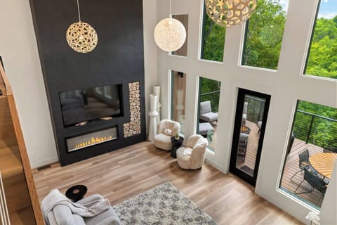 Relax in the grand living room featuring soaring cathedral ceilings, large windows, and a cozy fireplace. Perfect for gathering, unwinding, or simply taking in the stunning views in style and comfort.
