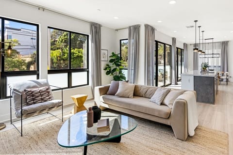 Sunlit living room with floor-to-ceiling windows and a comfortable neutral sofa, the perfect spot to unwind after a day exploring Echo Park.